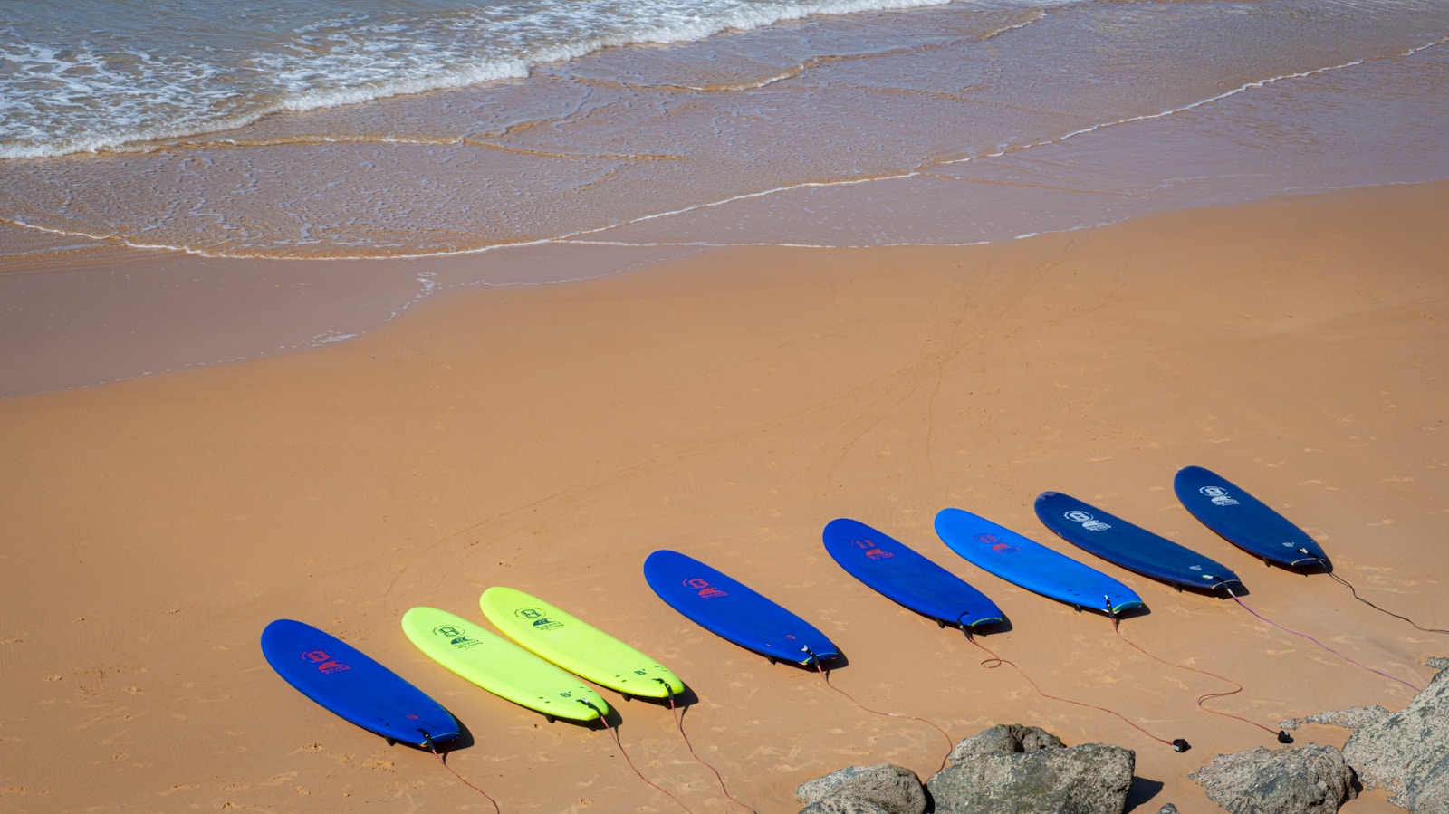 A row of surfboards sitting on top of a sandy beach